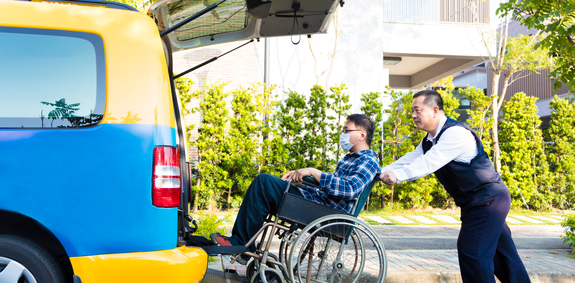 man helping a man in wheelchair to get into van