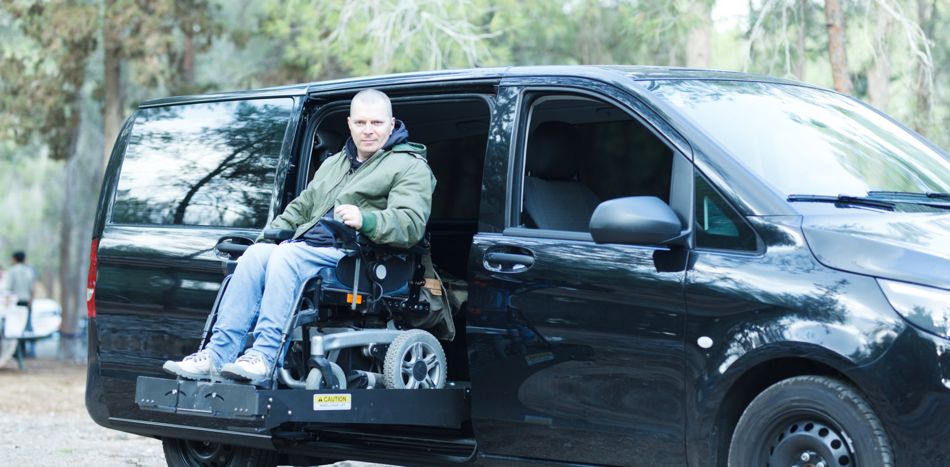 Man in wheelchair while wheelchair is being lifted by the van's platform